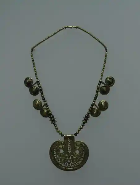 A gold necklace with swirling designs forming horns
